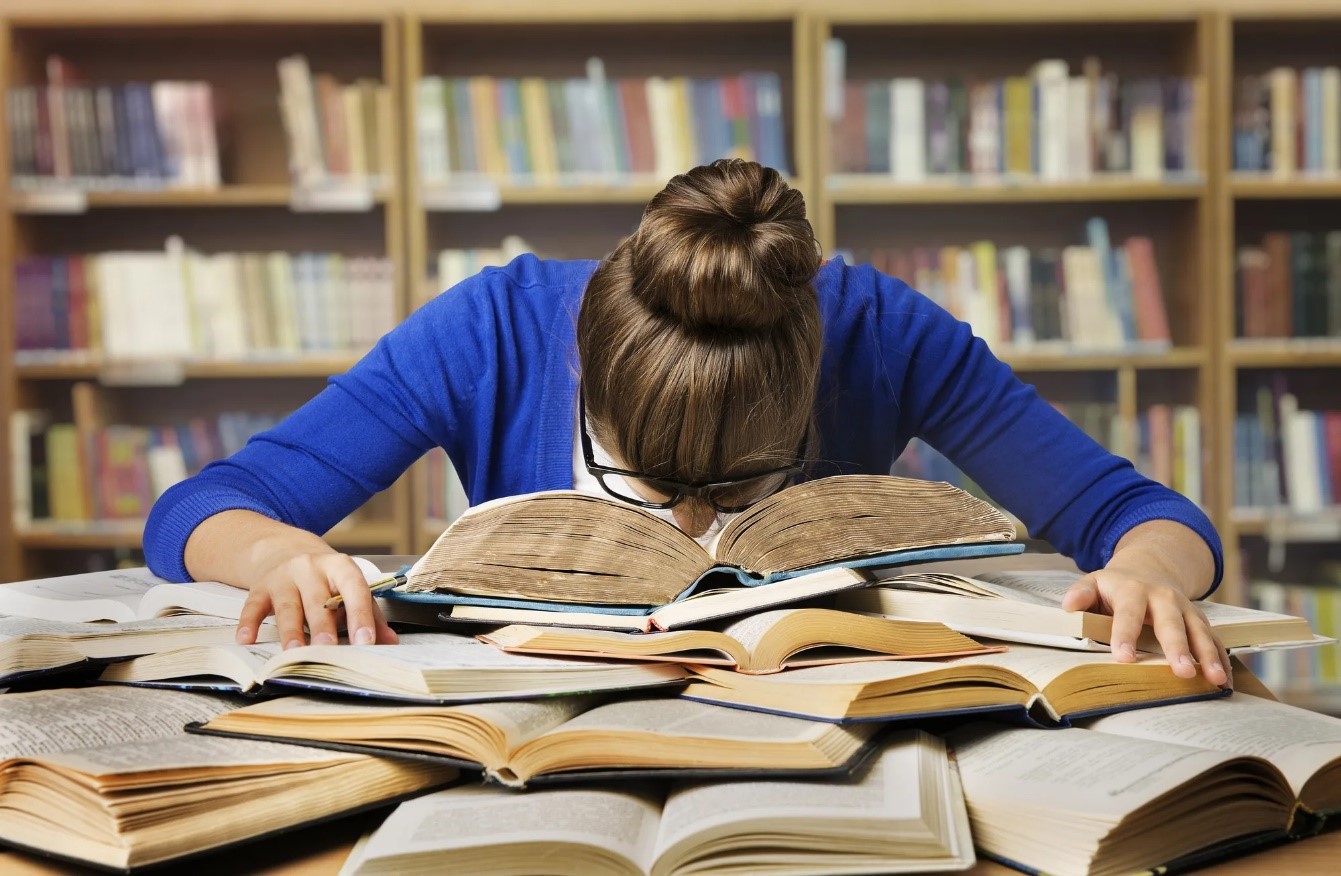 Девушка опустила голову в книги в библиотеке